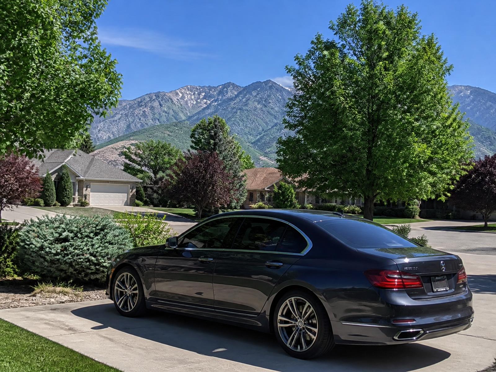 Professional headlight restoration near Sandy City Center — sedan parked outdoors in an established Sandy neighborhood on a bright sunny day with the Wasatch Mountains behind