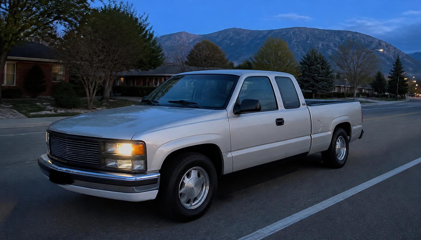 Mobile headlight restoration service in West Valley City — pickup truck parked on a wide west-side street at early evening with one restored headlight illuminated